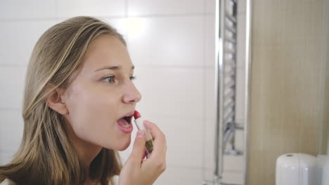 woman applying lipstick in bathroom