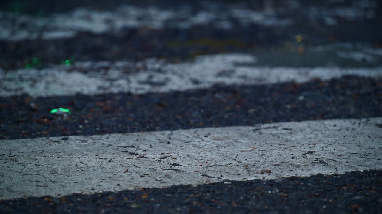 Green and red lights reflected on a wet pedestrian crossing from a traffic light