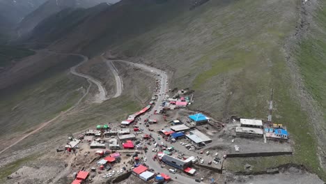 aerial view over mountain top shops and huts to reveal winding road at babusar pass