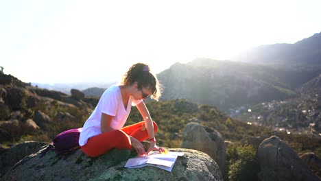 positive woman adjusting compass on map and sitting on hilltop