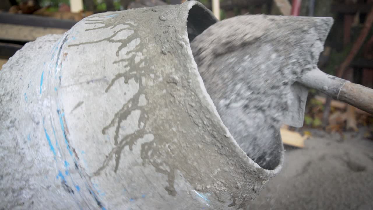 Construction worker shoveling gravel into a cement mixer