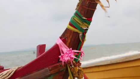 Colorful-ribbons-and-flowers-on-bow-of-traditional-wooden-fishing-boat-in-Thailand