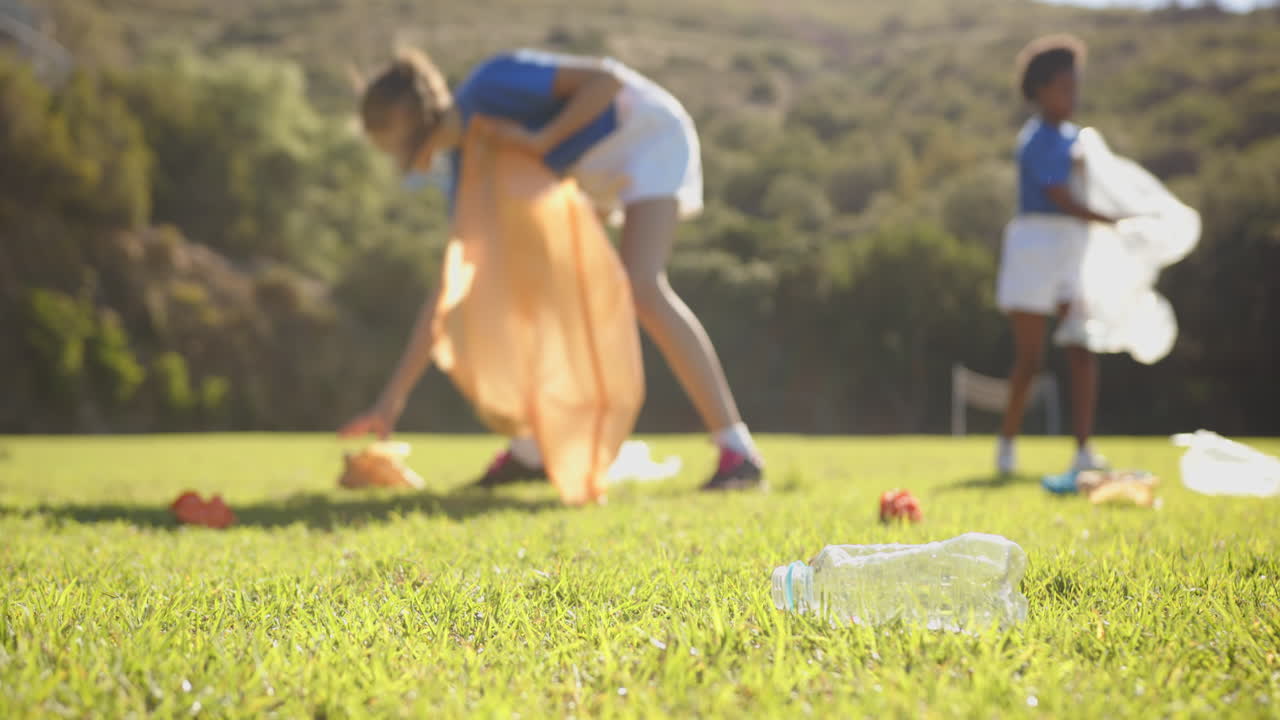 Picking up trash, girls cleaning school field, promoting environmental awareness