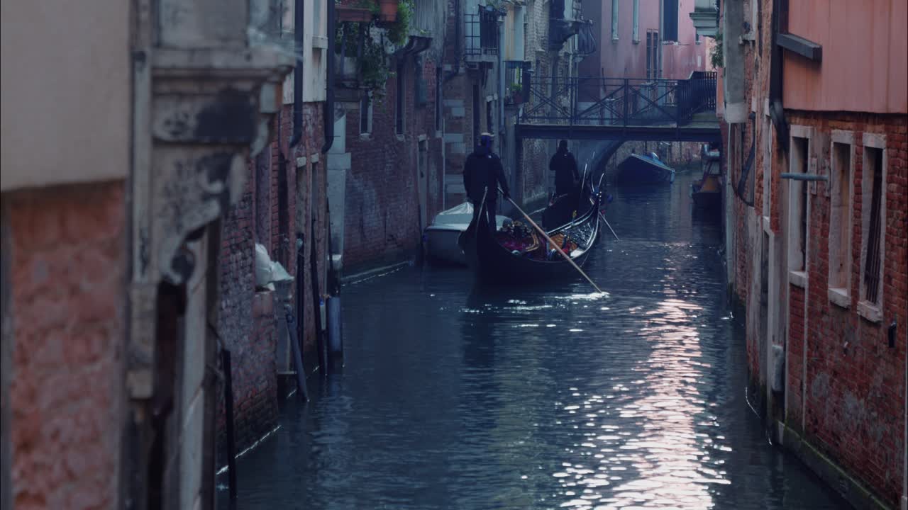 Des gondoliers ramant des gondoles traditionnelles à travers un canal étroit de Venise