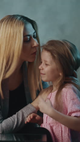 careful mother touches forehead of cute little daughter to check temperature at small table with pill bottle in darkened room at home slow motion