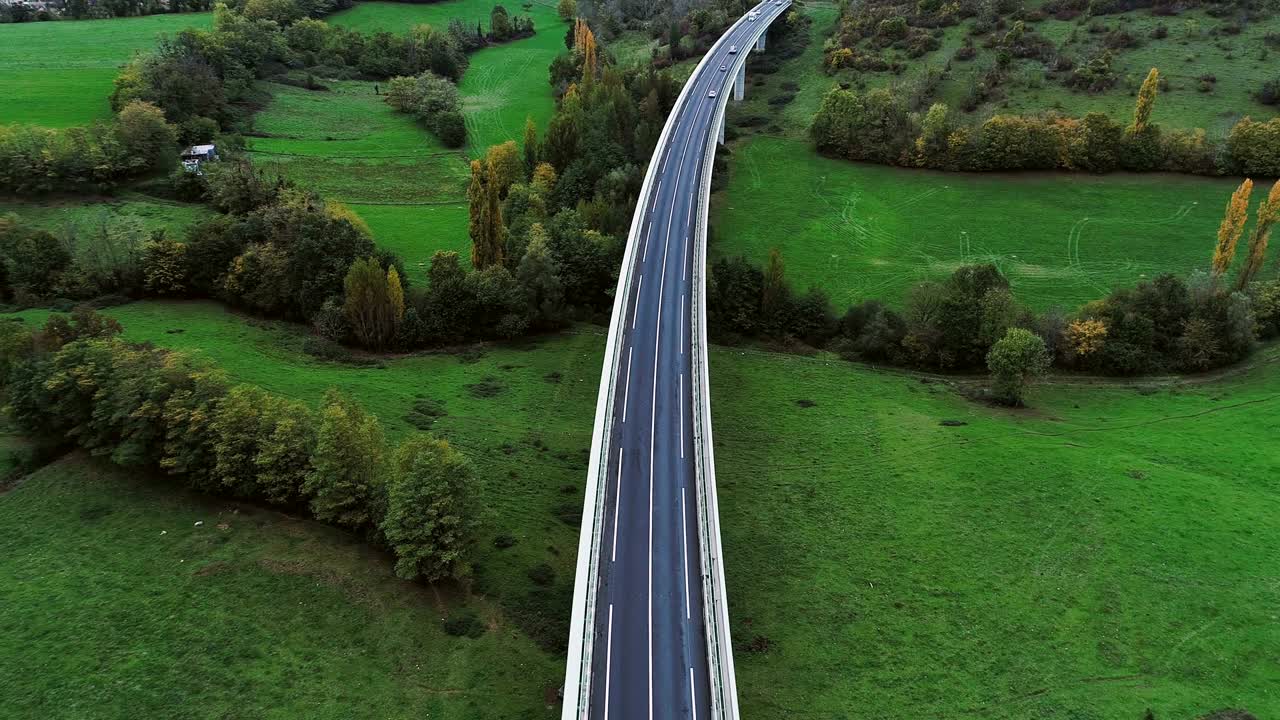 hermosa vista aérea sobre una carretera en francia. sólo campos de hierba y árboles alrededor de las carreteras. coches y camiones conduciendo en las carreteras bajo el sol.
