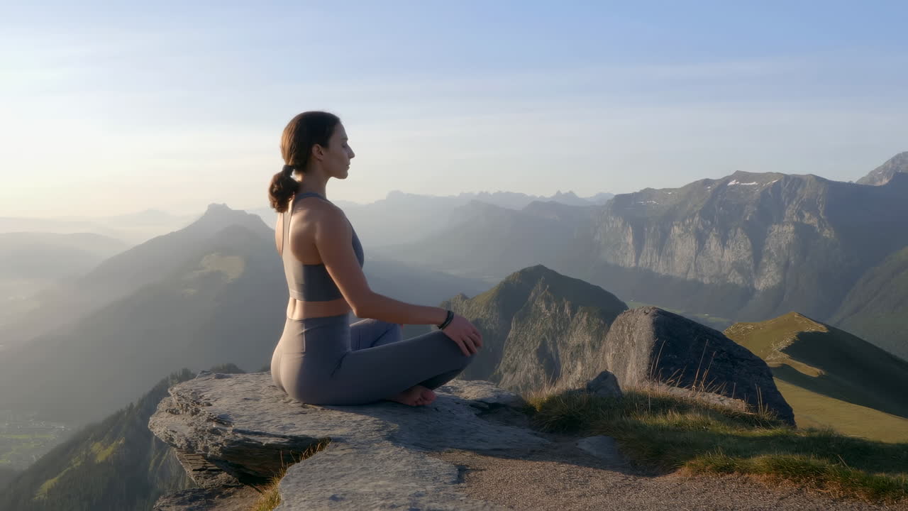 Woman Meditating on Mountain Peak at Sunrise