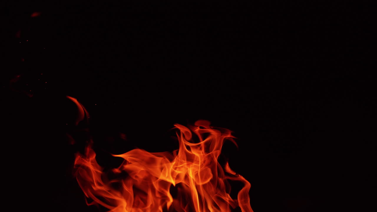 Flames of campfire stretch into the air. Beautiful view of bonfire isolated at black background. Close up.