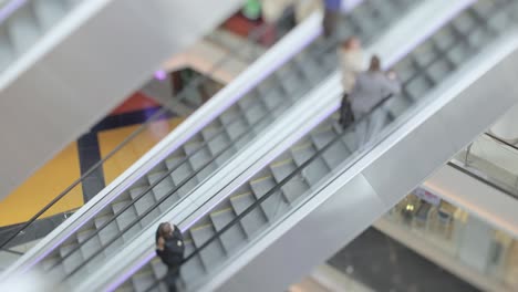 personas en movimiento en escaleras mecánicas en el centro comercial moderno. disparo con lente de cambio de inclinación con profundidad de campo súper superficial.
