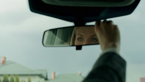 woman adjusting car rearview mirror