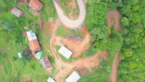 bird's eye view of small settlement panning towards forest via curvy roads