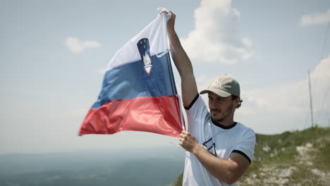 hiker holding up a slovenian flag to flutter in the wind