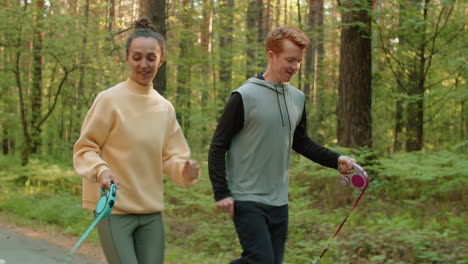 couple jogging in forest with dogs