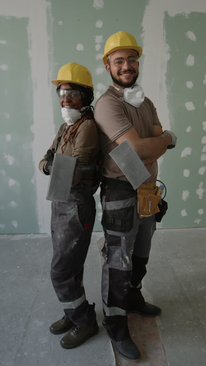 Construction workers standing back to back in front of drywall