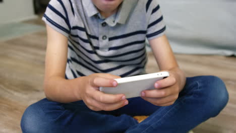 little boy sitting on the floor playing with a game console