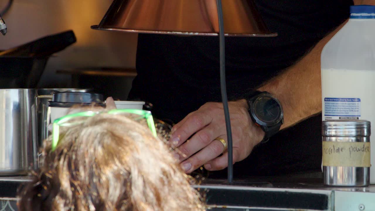 Barista pours steamed milk into takeaway cup at cafe counter, natural lighting, close-up shot