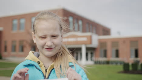 the child removes the protective mask from the face. standing in front of the school. end of quarantine concept