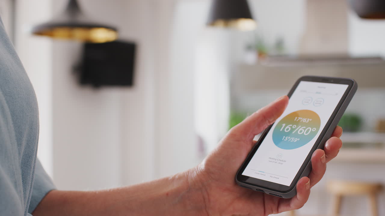 primer plano de una mujer usando una aplicación en un teléfono inteligente para controlar la temperatura de la calefacción central en la casa