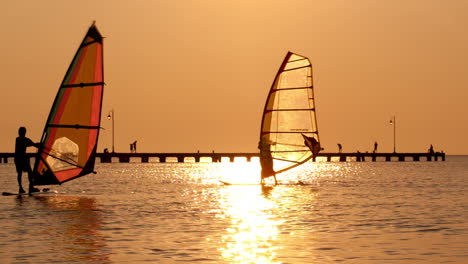 silhouettes of two surfers at sunset