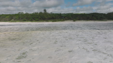 4K-Luftaufnahme-Eines-Australischen-Strandes-Mit-Meeresschaum,-Meeresschaum,-Strandschaum-Oder-Schaum,-Der-Durch-Die-Bewegung-Des-Meerwassers-Entsteht