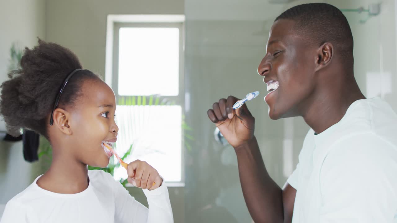 Video of african american father and daughter brushing teeth