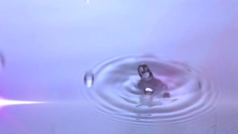 animación de gotas de agua cayendo en agua púrpura con luz brillante