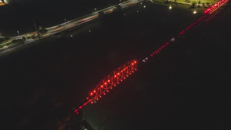 Ein-Drohnen-Luft-Hyperlapse-Einer-Geschäftigen-Stadt-Bei-Nacht,-Mit-Schnell-Fahrenden-Autos-Und-Einer-Beleuchteten-Brücke