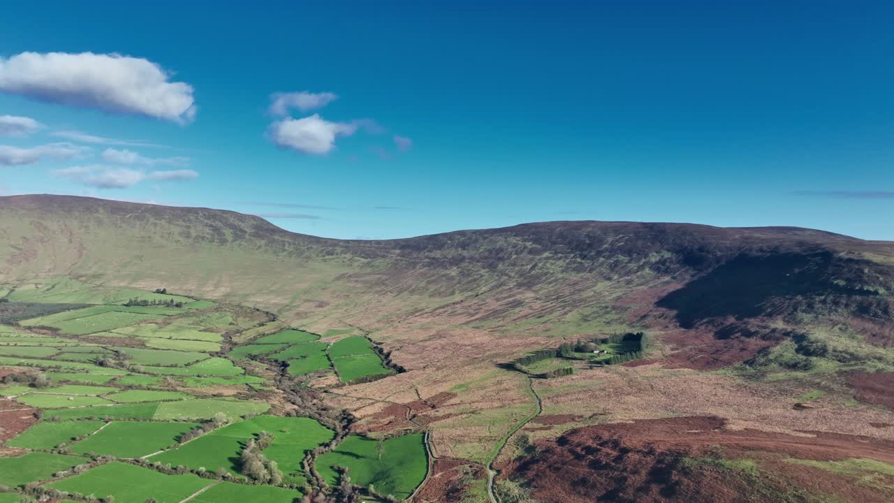 Epic Ireland drone rising over fertile farmland and mountainside in winter Comeragh Mountains Waterford