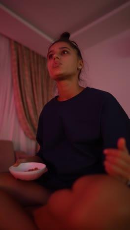 young woman watching tv and eating snack at night