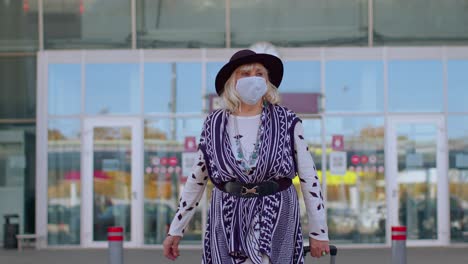 senior pensioner tourist grandmother wearing protective face mask, avoid coronavirus near airport
