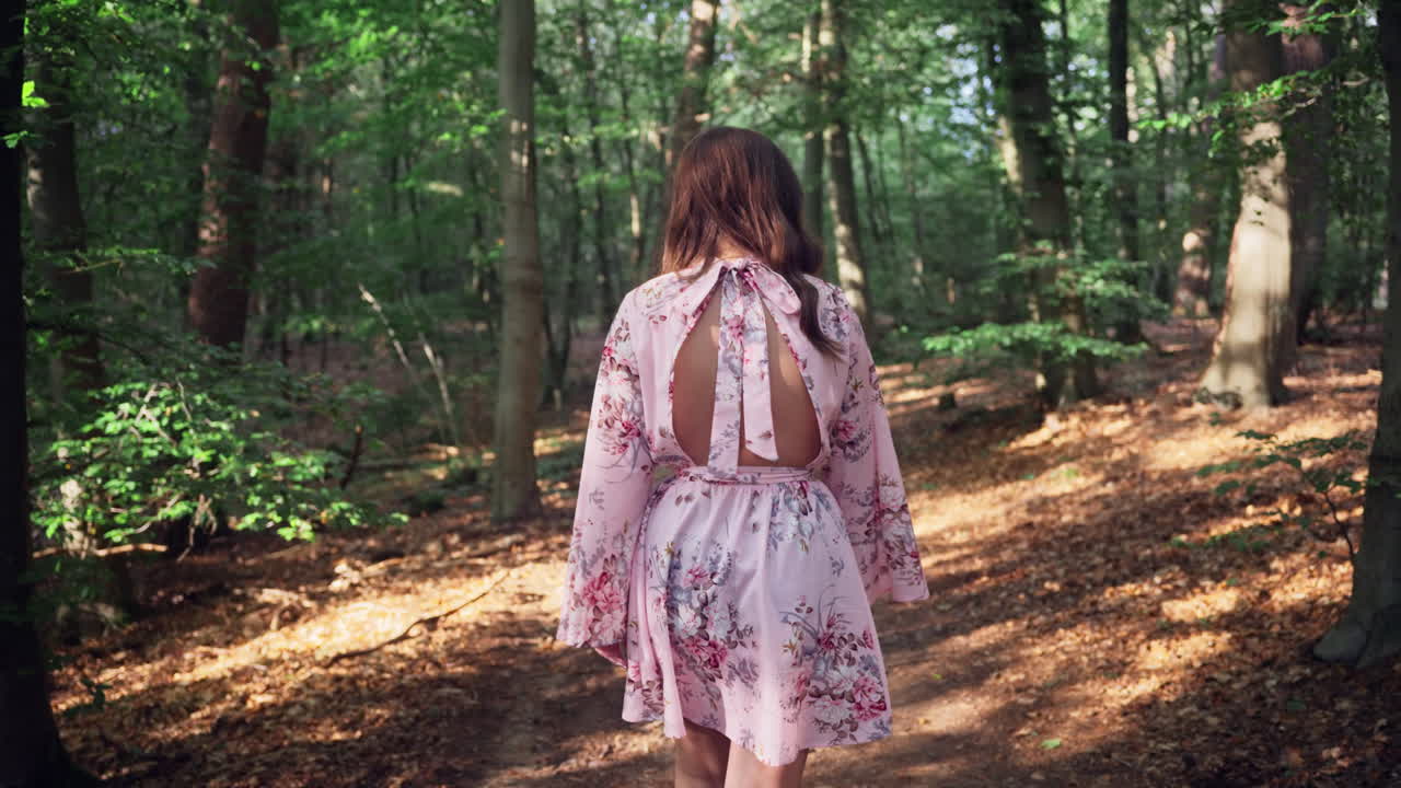 chica morena con vestido floral caminando en un bosque idílico en verano