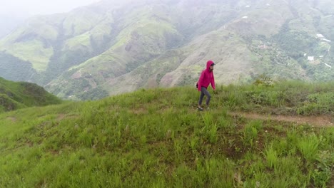 young woman hiking on green mountain alone, wear red jacket, el jarillo venezuela