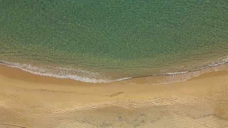 Vista-De-Arriba-Hacia-Abajo-De-Una-Playa-De-Aguas-Claras-En-España-Con-Tejidos-Tranquilos-Que-Se-Adentran-En-La-Costa