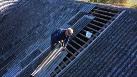 worker passing an asbestos slate for roof repairs, aerial view