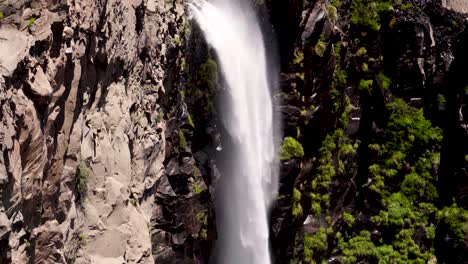 Close-up-view-of-a-waterfall-being-hit-hard-by-the-wind,-thus-generating-the-inverted-movement-of-its-bed