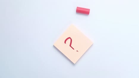 person writing a question mark on a sticky note