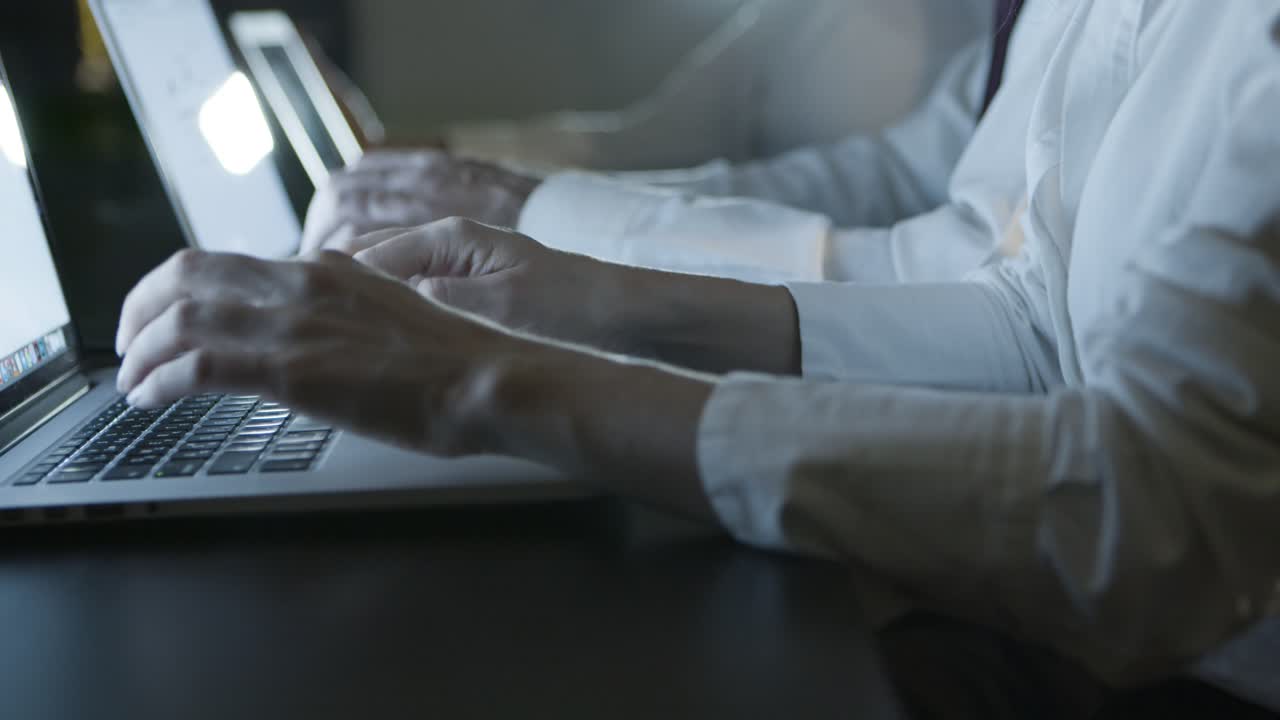 Cropped shot of people using computers in dark office