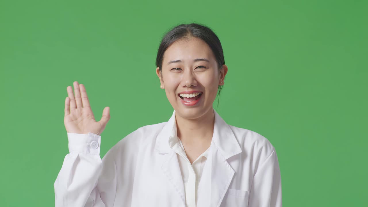 실험실 코트를 입은 미소 짓는 아시아 여성이 흔들고 있습니다.