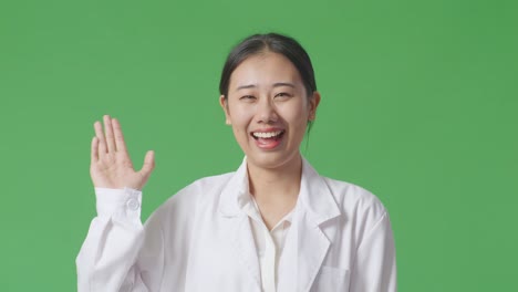 smiling asian woman in lab coat waving