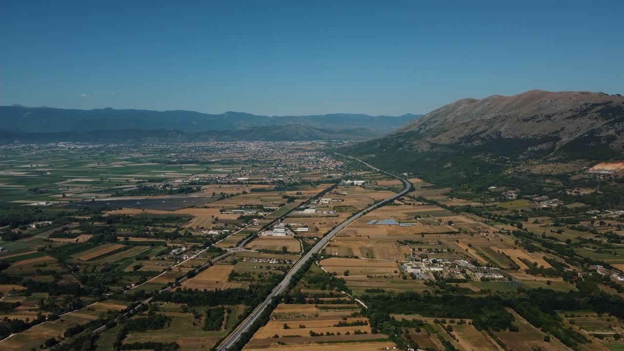 Aerial view of landscape with mountains, road, and fields