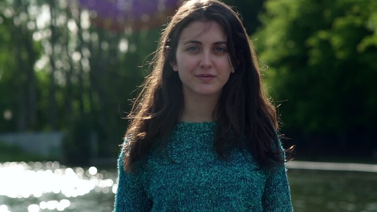 Retrato de una elegante y hermosa modelo italiana caminando en un parque tranquilo, luciendo un suéter brillante en Londres, Reino Unido