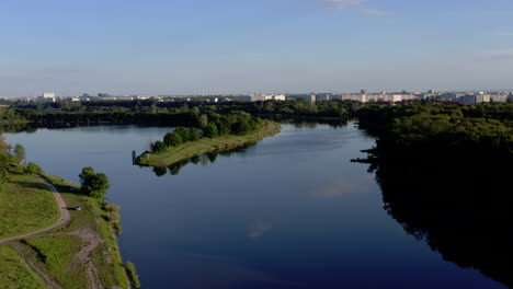 Aerial-shot-of-a-wide-calm-river-with-a-large-city-in-the-distance