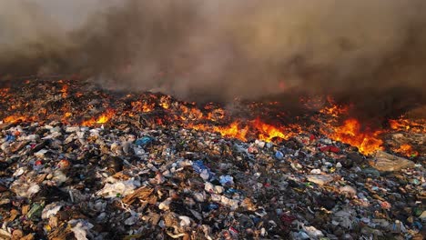 raging fire spreads through landfill as thick black smoke rises over burning waste