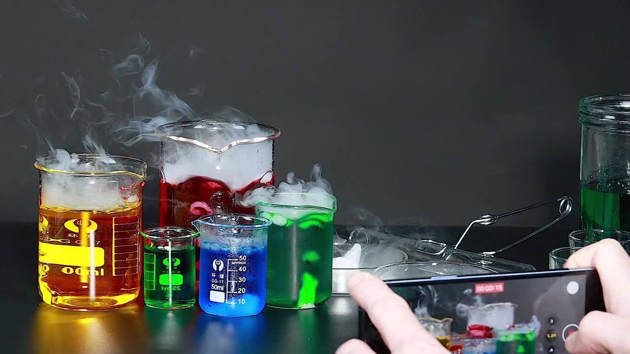 Colorful liquids in beakers with smoke effects, photographed during a chemical reaction.