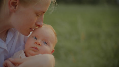 mother hugging and kissing newborn at sunset