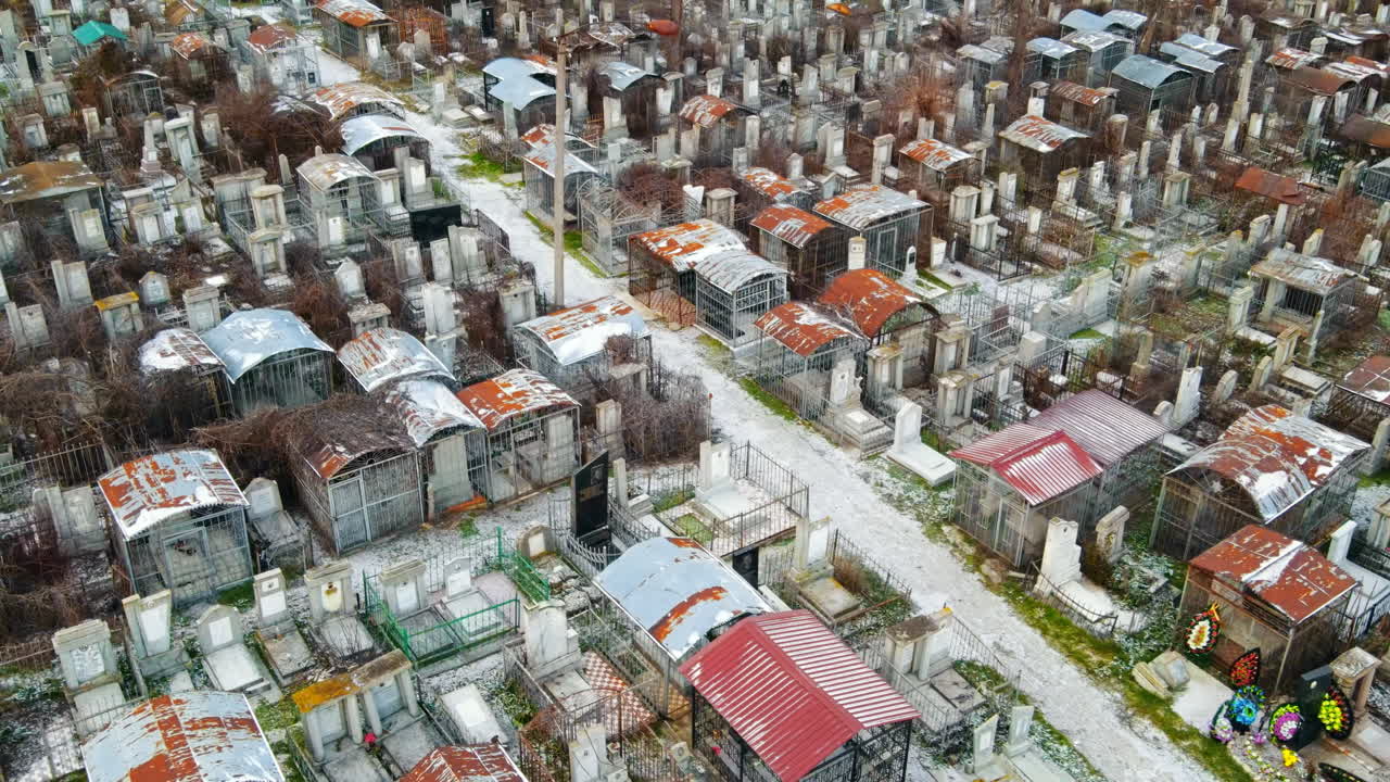 Aerial drone view of a cemetery in Chisinau, Moldova. Multiple graves, crypts, walkway, Cloudy weather, bare trees, winter