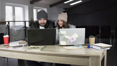 Young-man-and-woman-working-in-creative-office.-White-and-black-laptops-on-the-table.-Modern-design-of-the-office.-Shot-in-4k