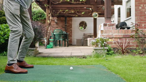man playing golf in backyard