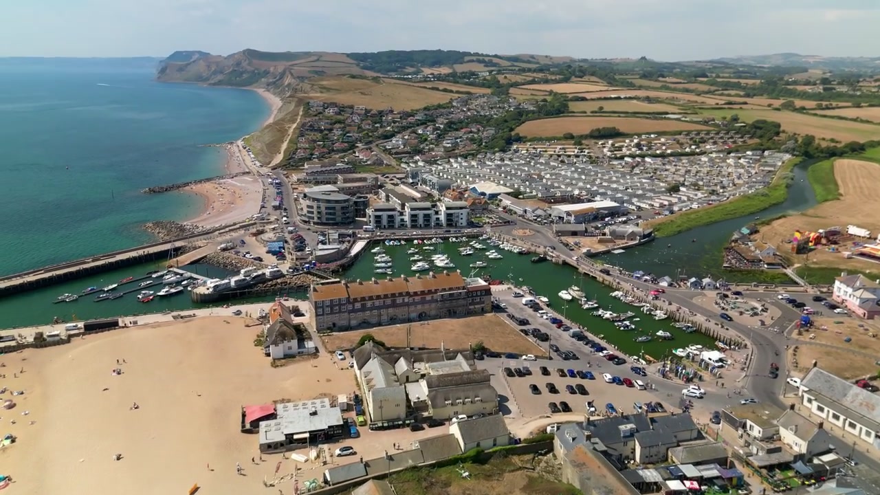 Vista aerea da drone di West Bay nel Dorset, Inghilterra, che mostra il porto, la marina, la spiaggia sabbiosa, il fiume Brit, la città costiera e la campagna circostante lungo la Costa Giurassica