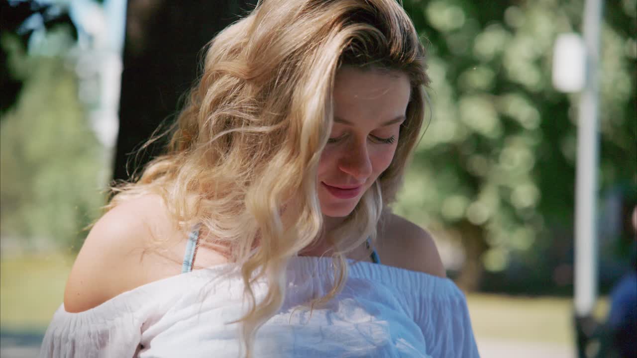 Blije jonge blonde vrouw lacht in een zonnig park